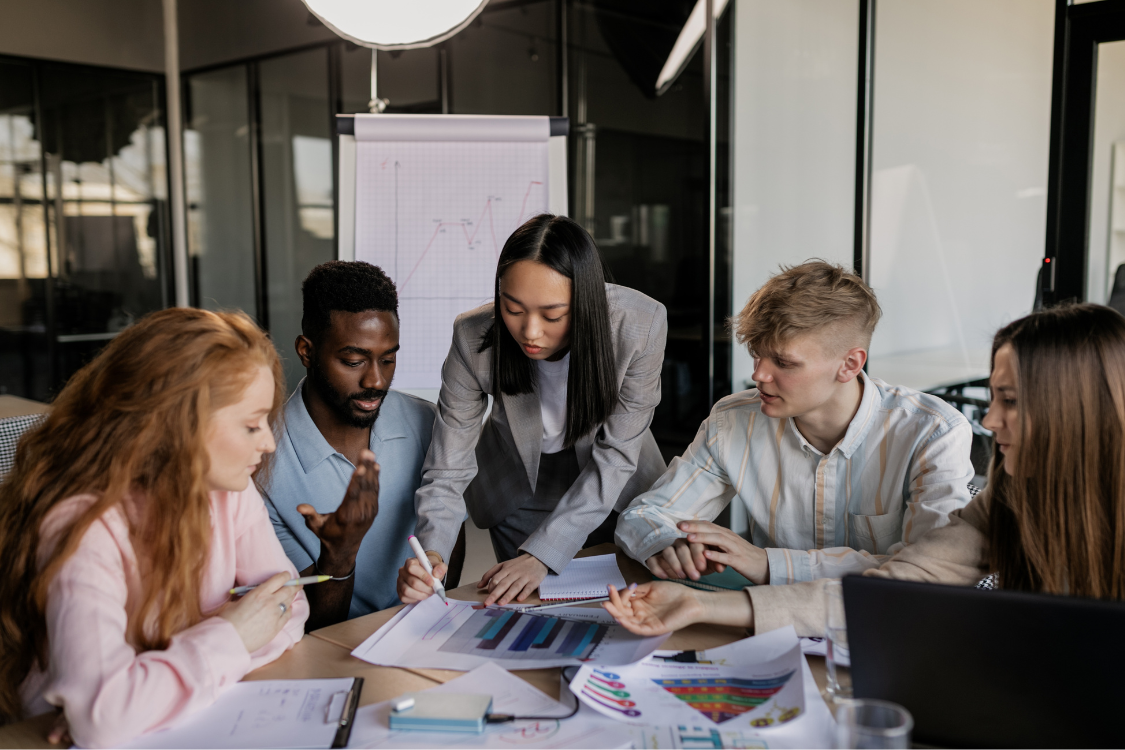 Diverse startup team collaborating around business charts in a physical office setting
