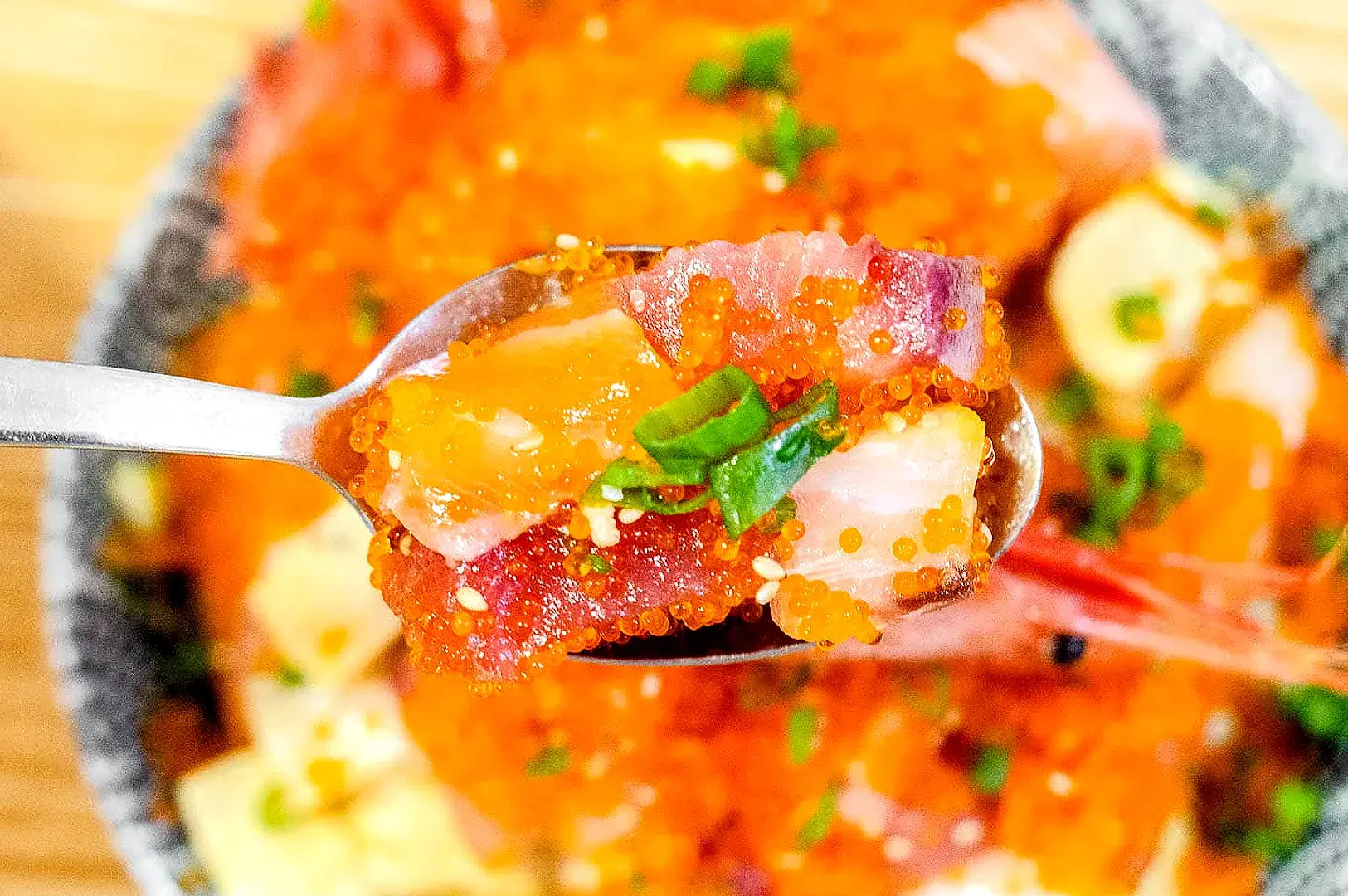Close-up of chirashi sushi with sashimi, ikura, salmon, tuna, and egg yolk at Chirashizushi Shou