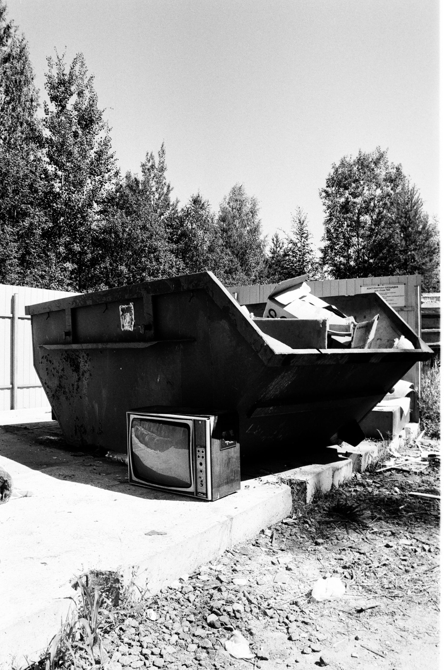 Black and White Photo of Dumpster With TV