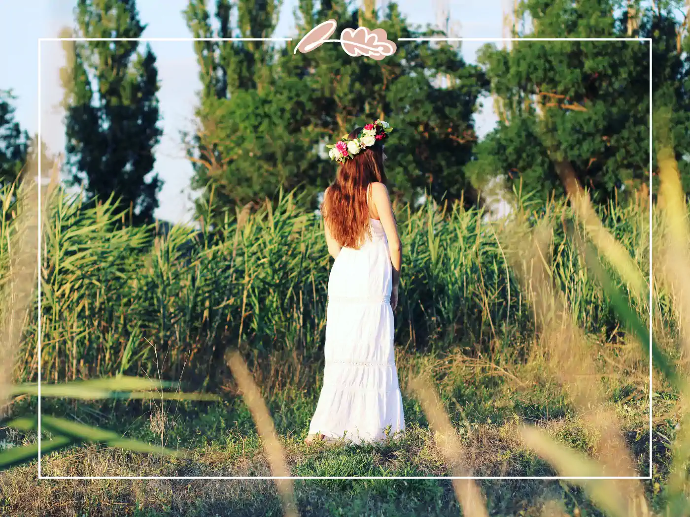 A woman in a white dress with her back to the camera, standing in a field wearing a colorful floral crown. Summer Serenity Floral Crown by Fabulous Flowers and Gifts.