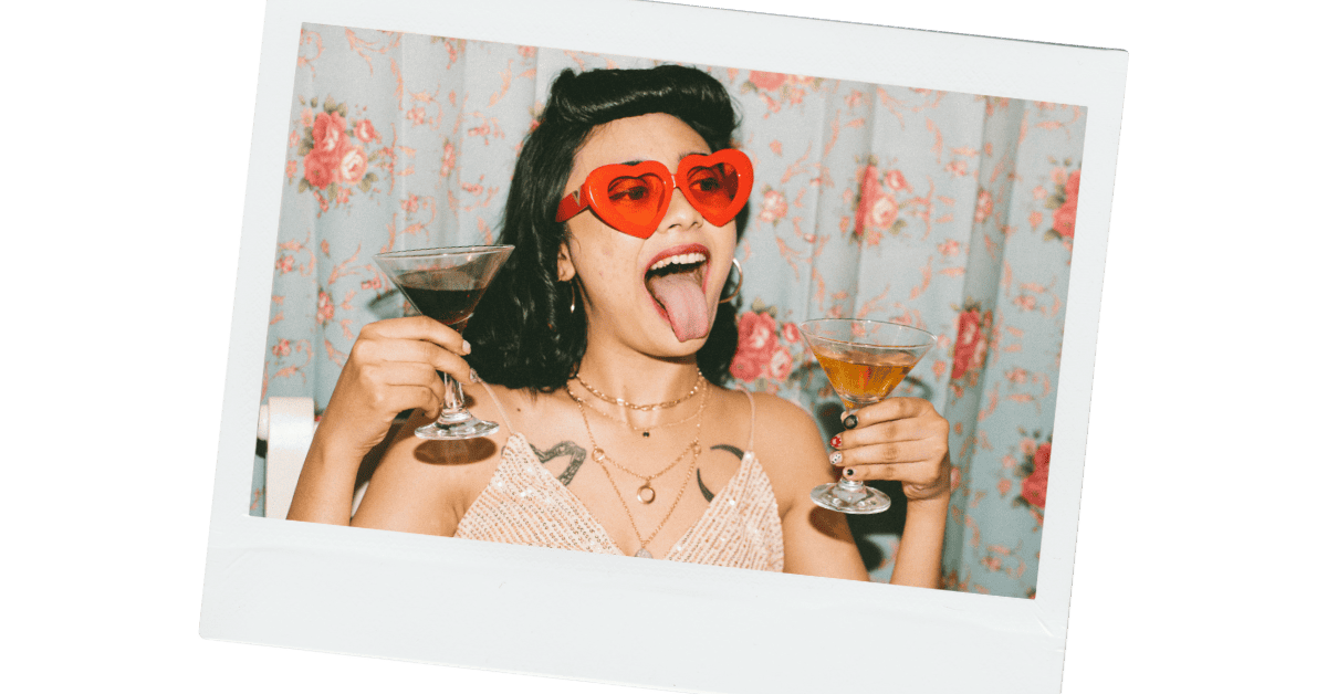 A woman drinking and partying with her tongue out.