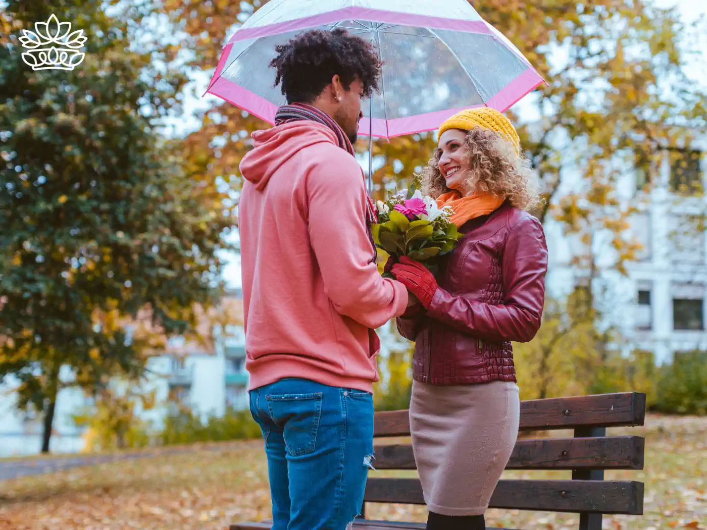 Young couple sharing a romantic moment under an umbrella in a park, with the man presenting a bouquet of mixed flowers, showcasing heartfelt gestures with flower bouquets under R500 from Fabulous Flowers and Gifts.