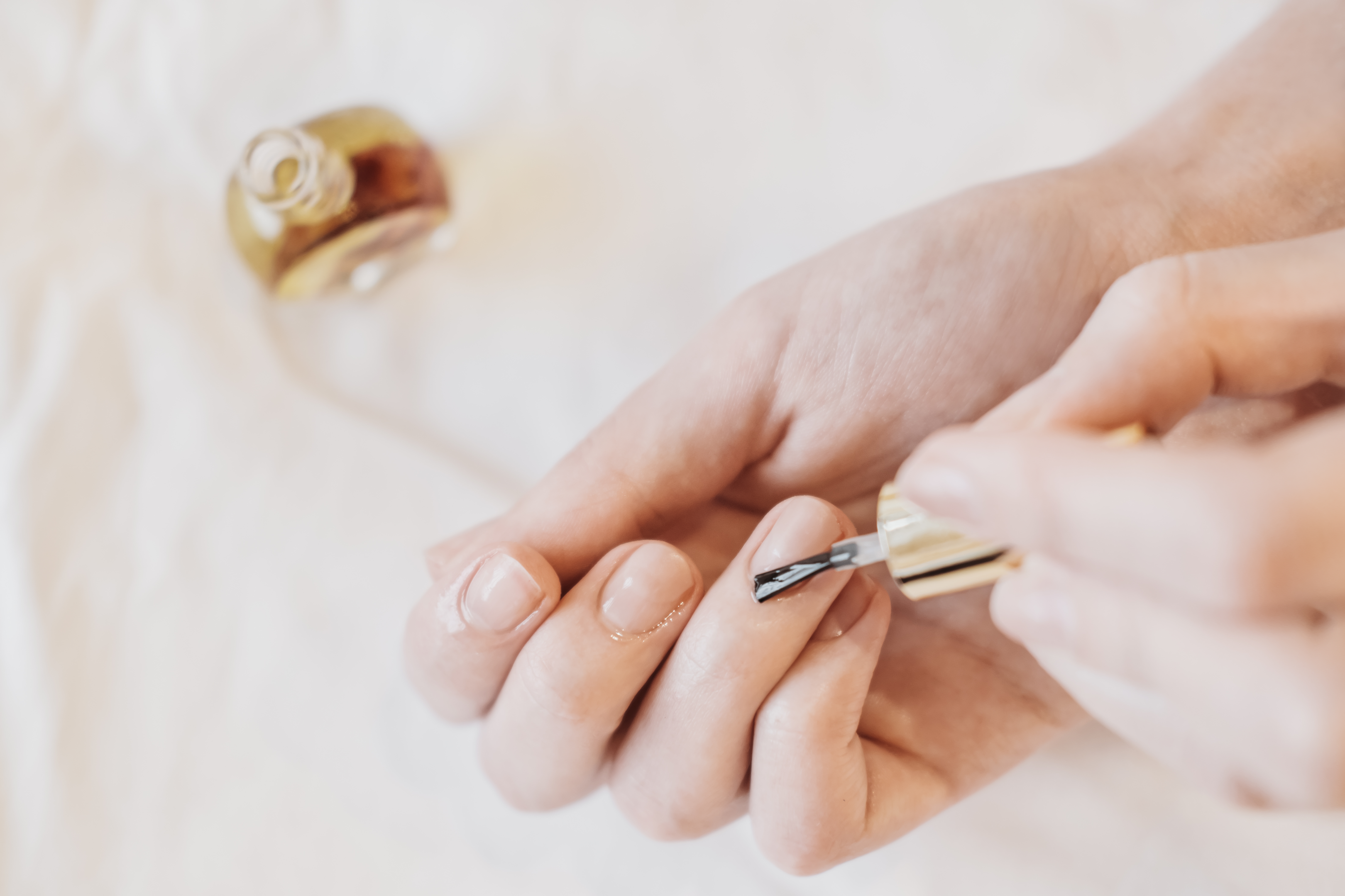 A woman applying cuticle oil to her nails after gel polish removal