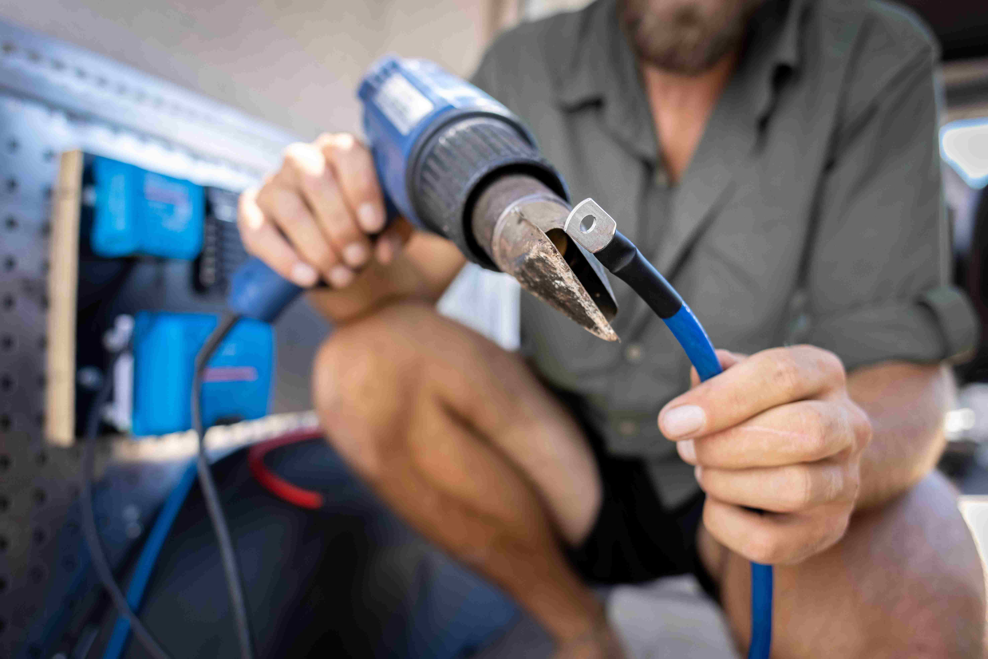 Homem utiliza tubagem termorretráctil num cabo elétrico para conversão de autocaravana