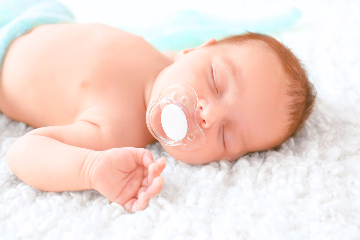 Newborn with binkie and pacifier in mouth