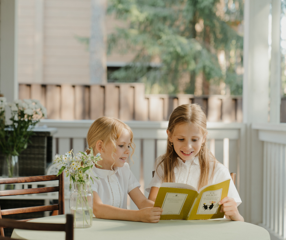 two children sit on their porch reading a book