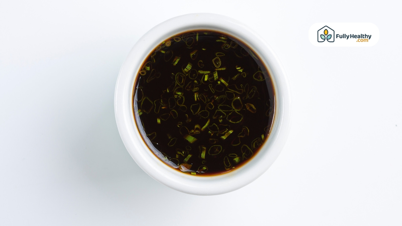 White bowl filled with soy sauce and chopped green onions