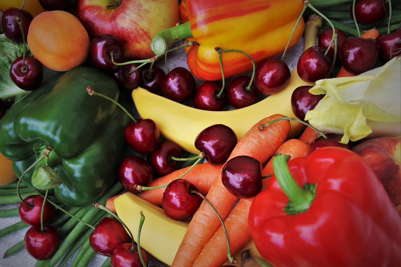 An image of a table of carrots, peppers, cherries, and apples.