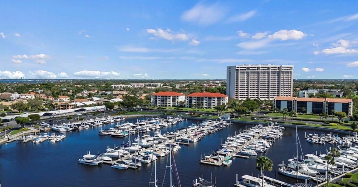 The image depicts a scenic golf course fairway set against rolling hills, with water hazards strategically placed throughout the landscape. Golfers can be seen enjoying their game on the green, showcasing the vibrant outdoor lifestyle that the Landings community in Fort Myers, FL, offers.
