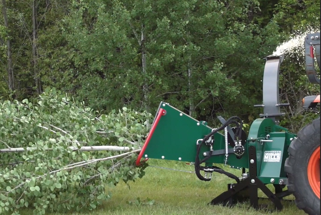 A hydraulic infeed grabs tree branches into a Woodland Mills Wood Chipper.