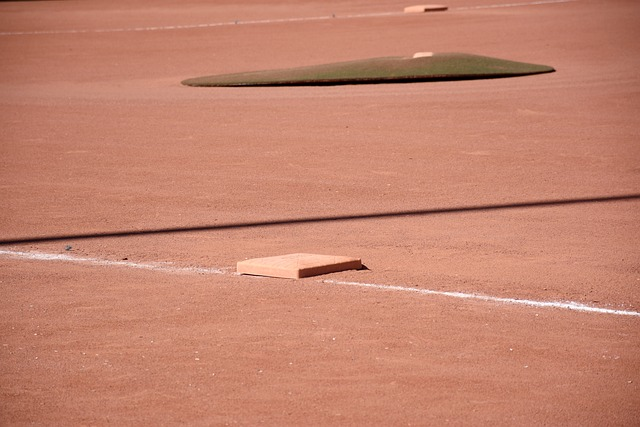 A person chalking a foul line and a coaches box
