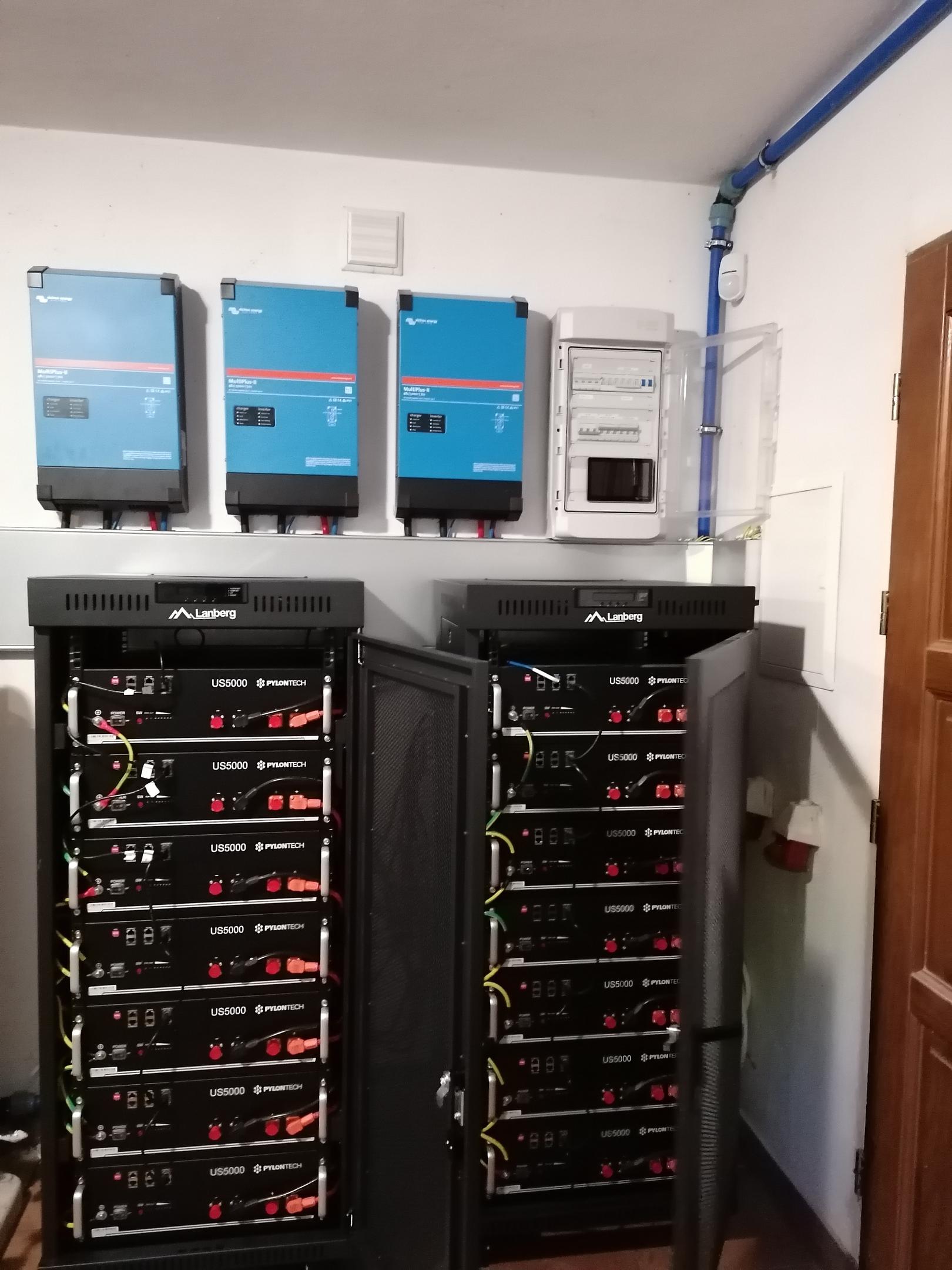 Na obrazie widoczny jest nowoczesny dom z panelami fotowoltaicznymi na dachu oraz magazynem energii umieszczonym w garażu, który może być częścią systemu victron energy. Całość ukazuje zastosowanie energii słonecznej do zasilania budynku, zapewniając niezależność energetyczną i możliwość zdalnego monitorowania.