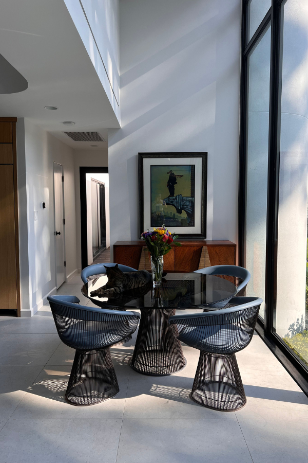 a breakfast room with large windows, a table with blue chairs, and a framed painting