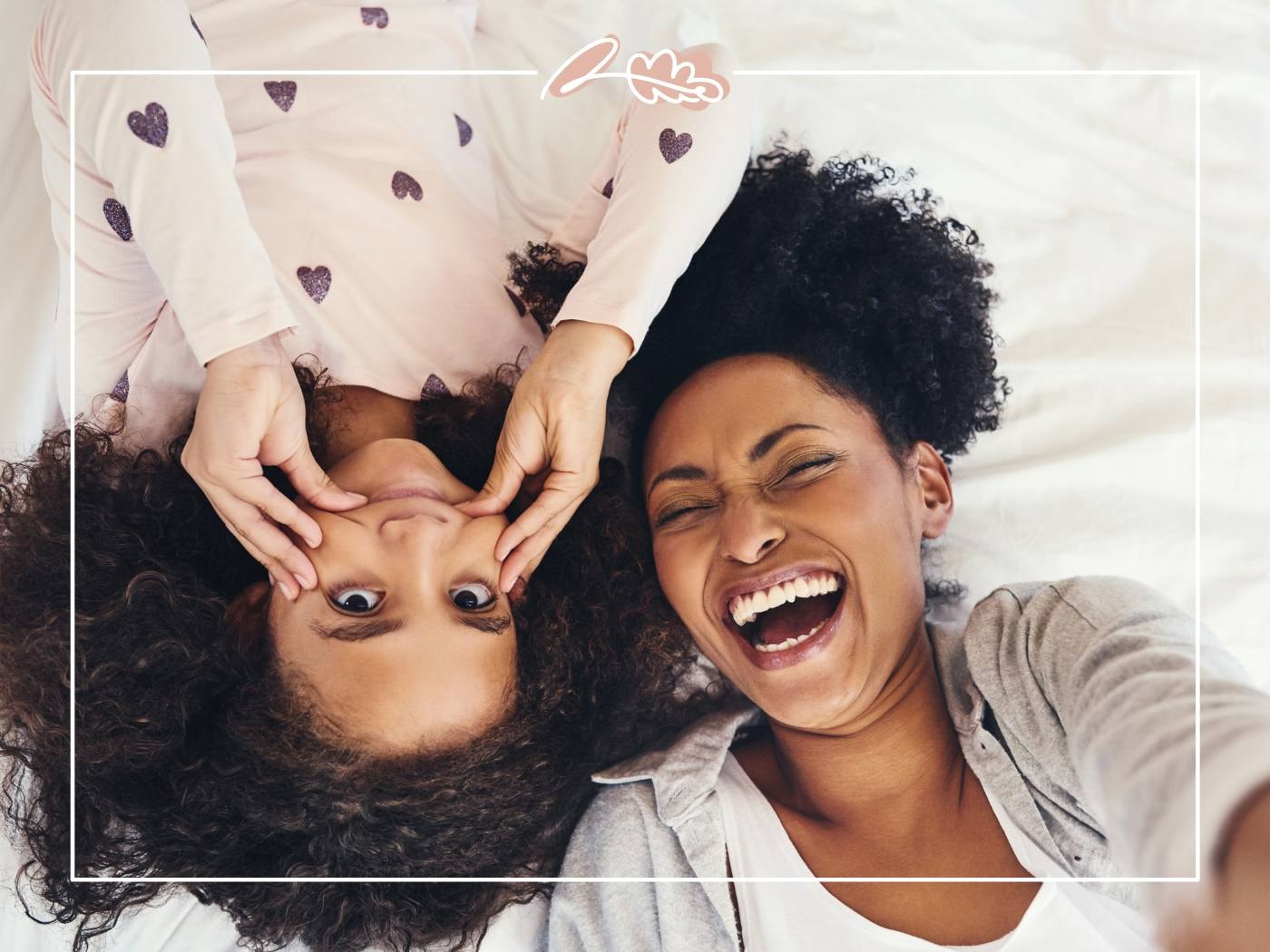 Mother and daughter lying on a bed, sharing playful laughter. Capturing the fun, lighthearted moments in their relationship.