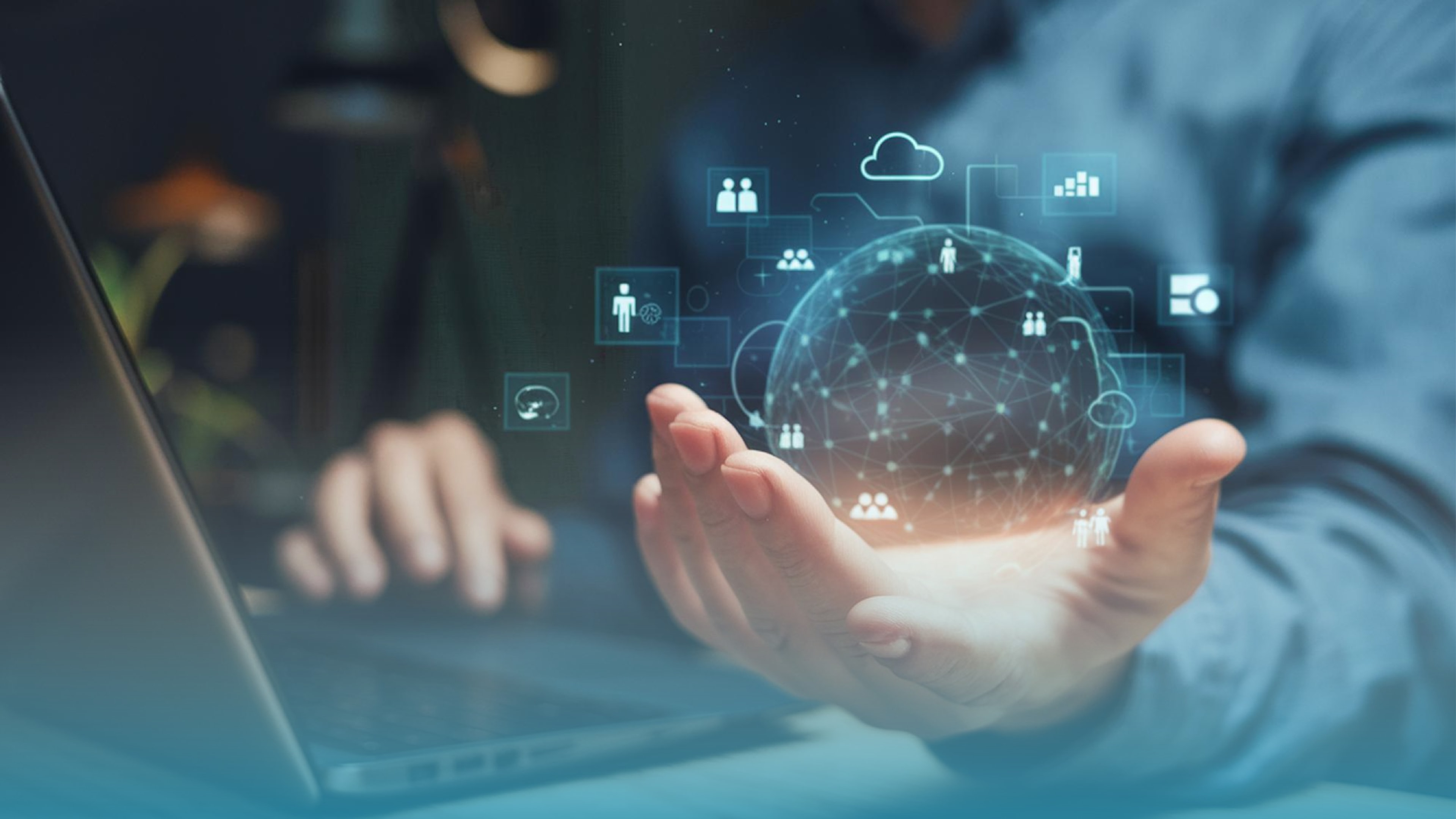 Person working on a laptop with a digital network graphic of a globe and connected icons projected above their hand, symbolizing interconnected business operations and connected devices.