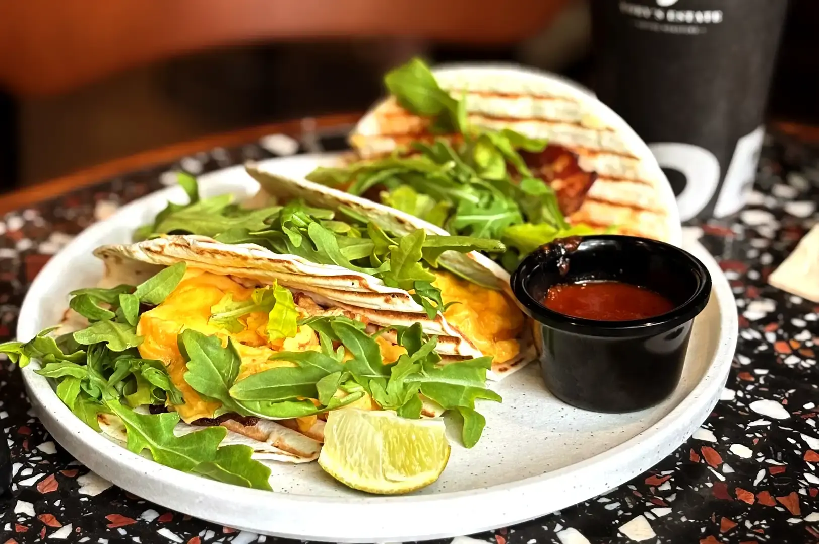A plate of hearty breakfast tacos served with fresh arugula and a side of chilli jam at Toby's Estate Singapore.