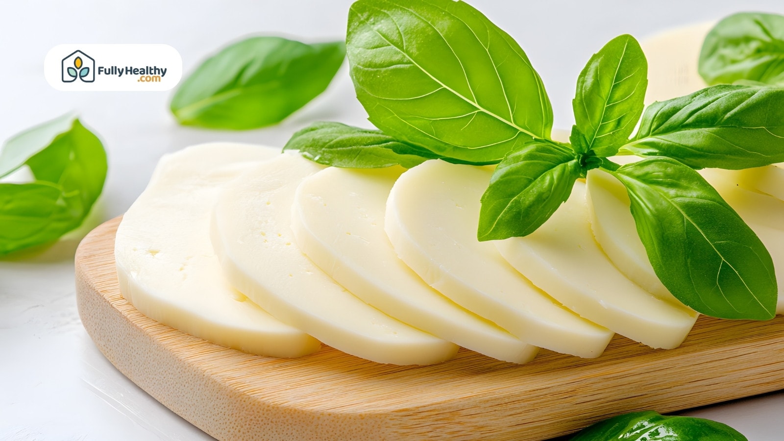 Sliced mozzarella cheese with fresh basil leaves on wooden cutting board