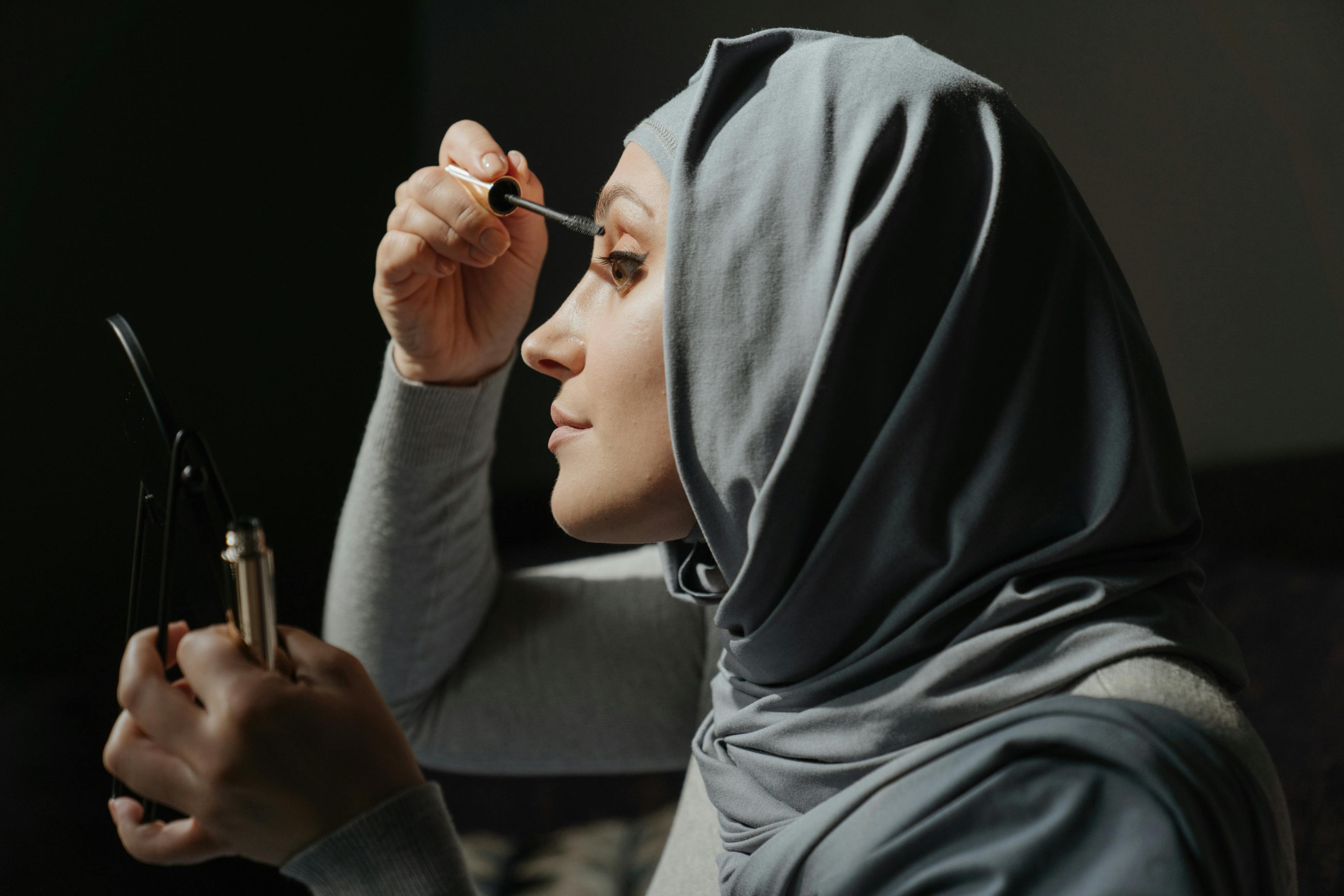 A hijabi applying mascara