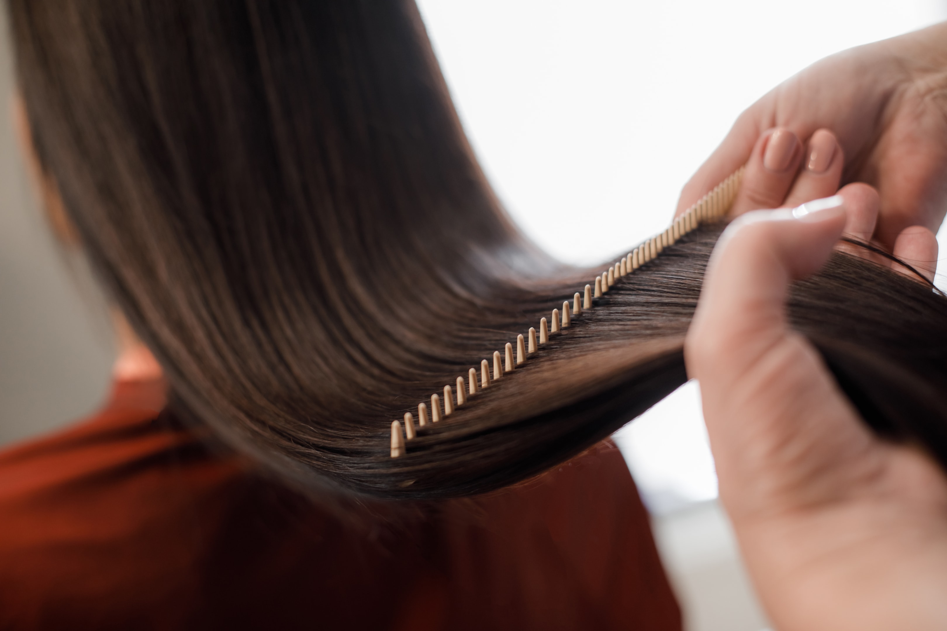 a hand is shown combing the long hair of a woman
