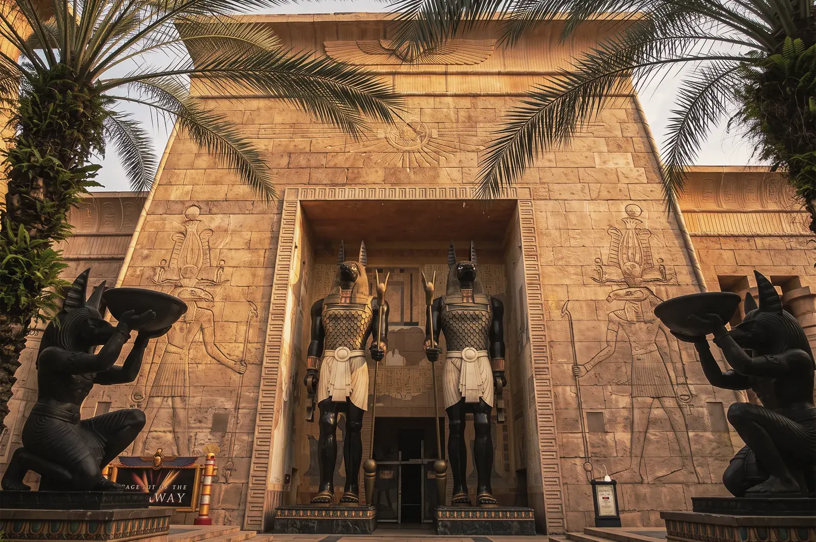 Ancient Egypt zone at Universal Studios Singapore with towering Anubis statues, palm trees, and hieroglyphic carvings on temple walls.
