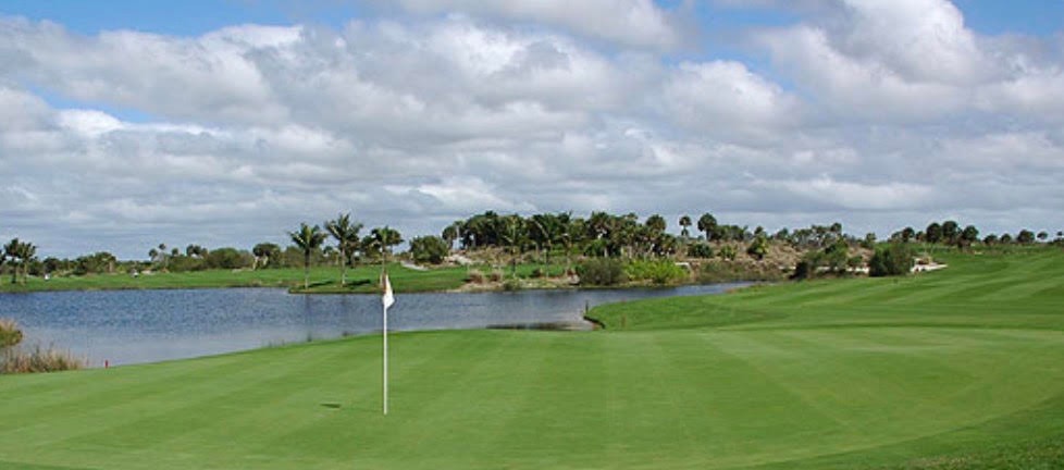 The image depicts a championship golf course fairway surrounded by luxury tower residences, showcasing pristine landscaping and a scenic backdrop. This luxurious setting exemplifies the high-end living found in Marco Island's golf course communities, complete with spacious outdoor terraces and access to exclusive amenities.