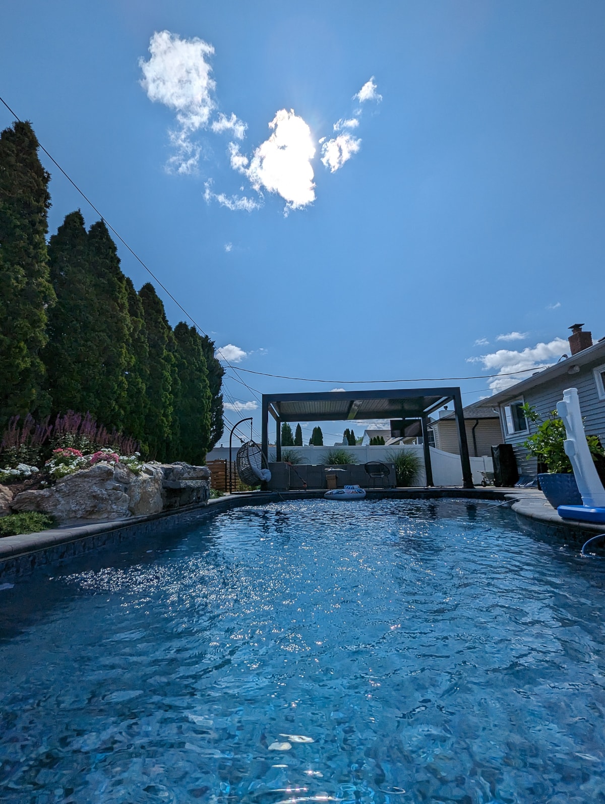 Poolside black pergola installed as a patio cover with outdoor furniture.