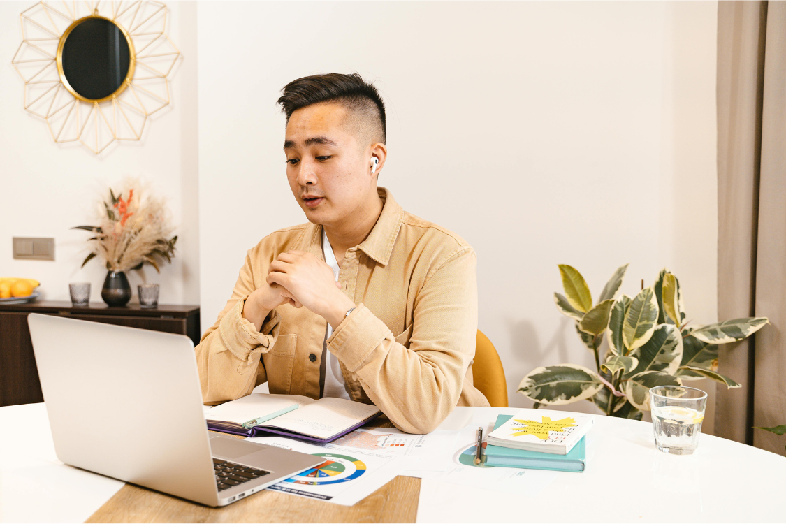 Remote worker attending a video call from a home office with laptop and documents