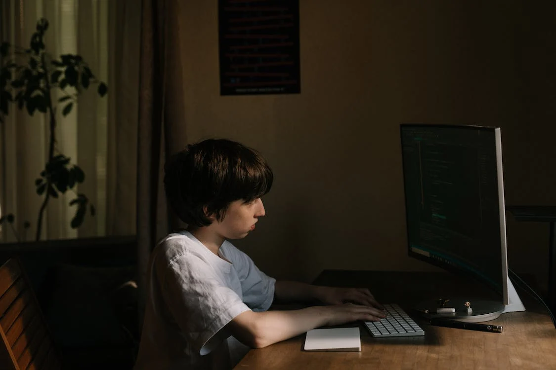 a boy is working in a JavaScript file on a desktop computer