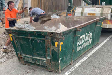 Skip bin with ramp/door at one end for heavy waste