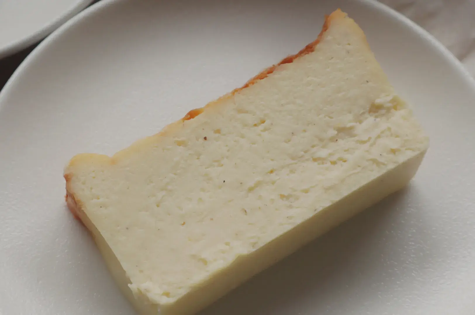 A rectangular piece of creamy white cheesecake on a white plate.
