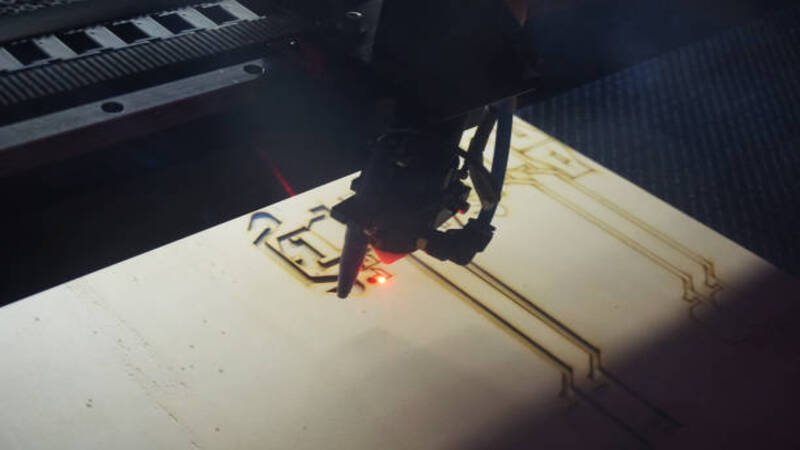 Laser machine engraving patterns on a plywood sheet.