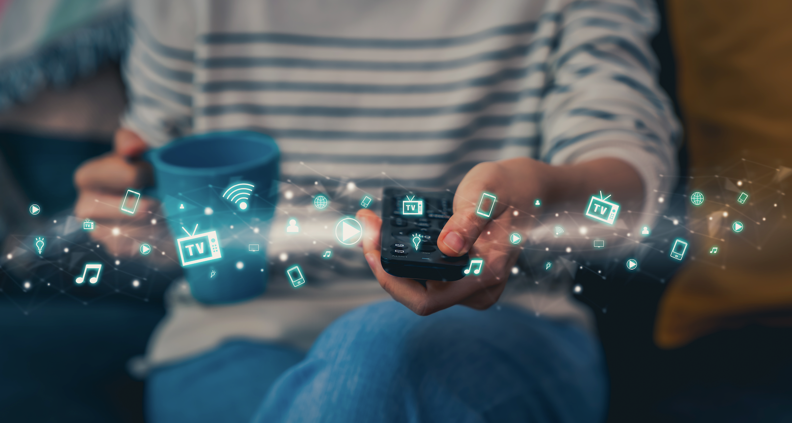 a person holding a tv remote and a mug presses a button behind streaming tv icons that float around