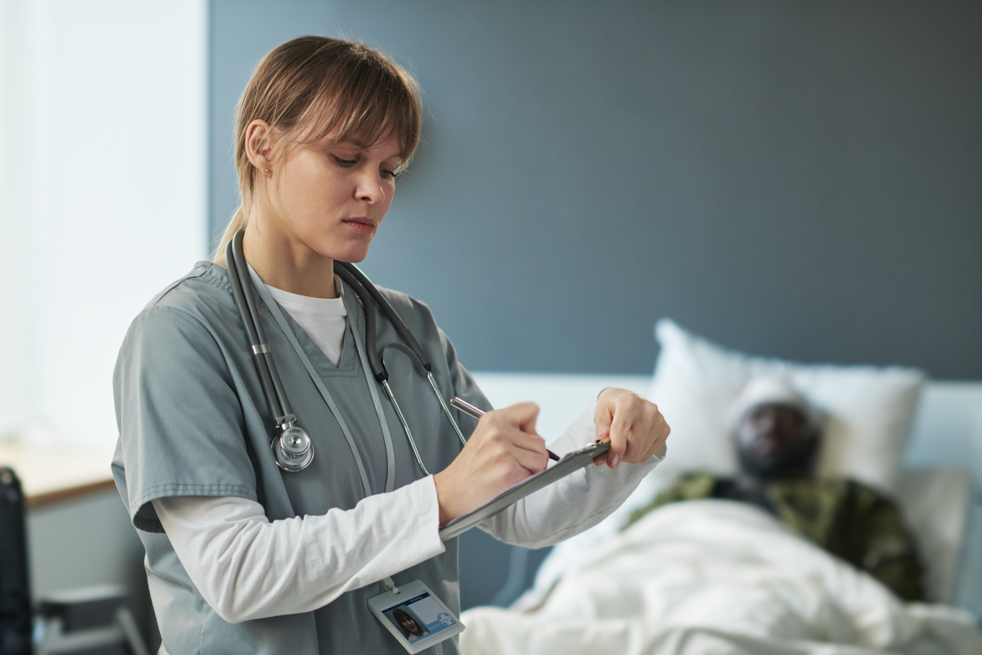 nurse-in-gray-scrubs-writing-on-clipboard
