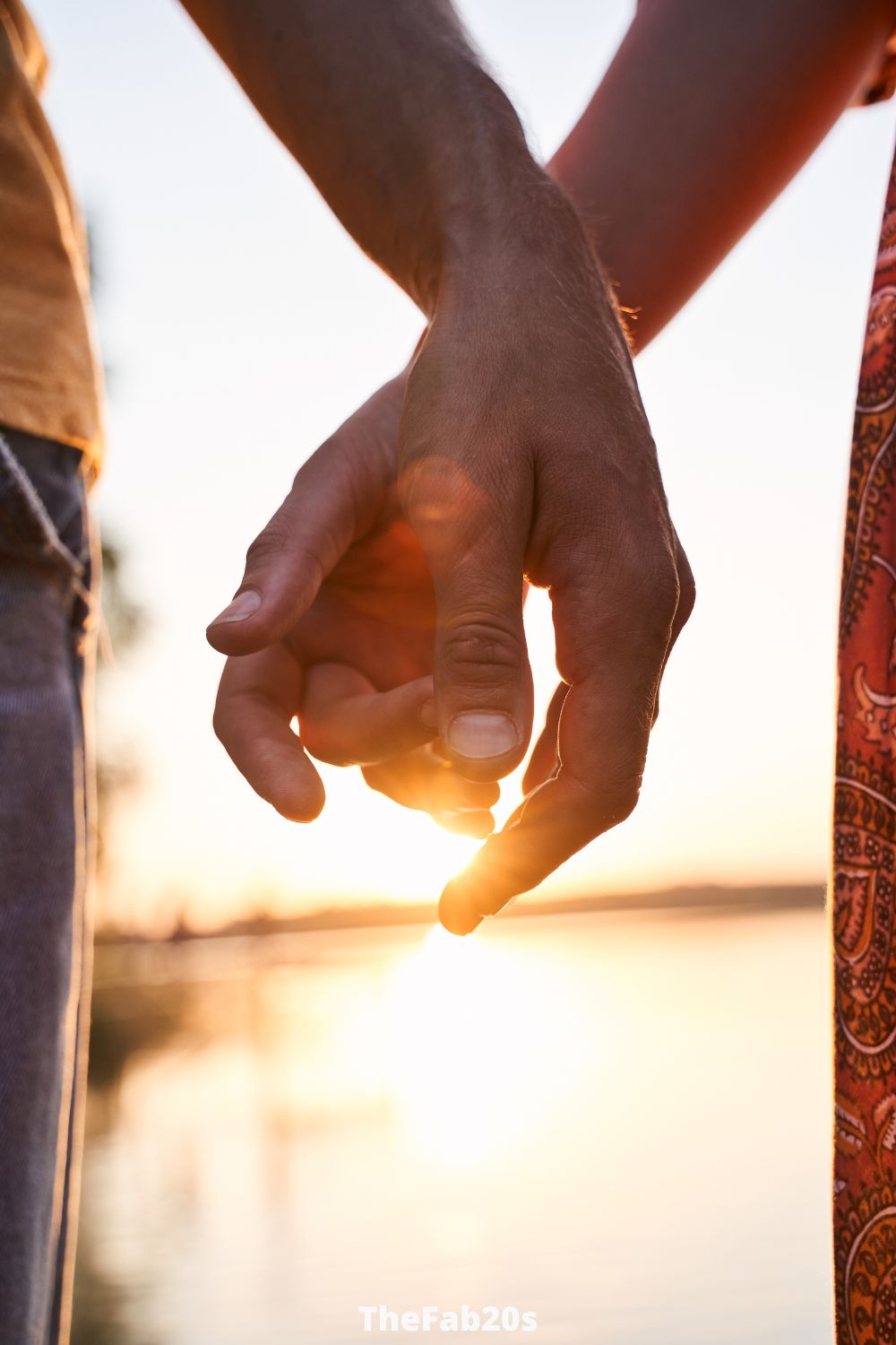 Couple holding hands with sunset in the background -