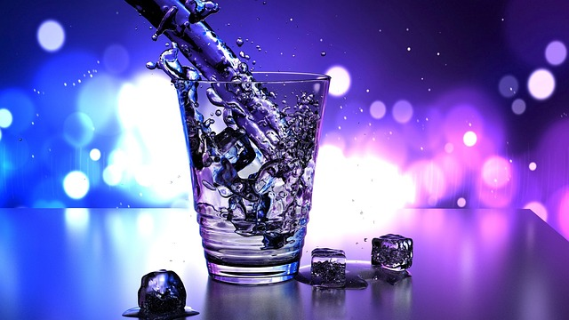 An image of water being poured into a glass with ice. 
