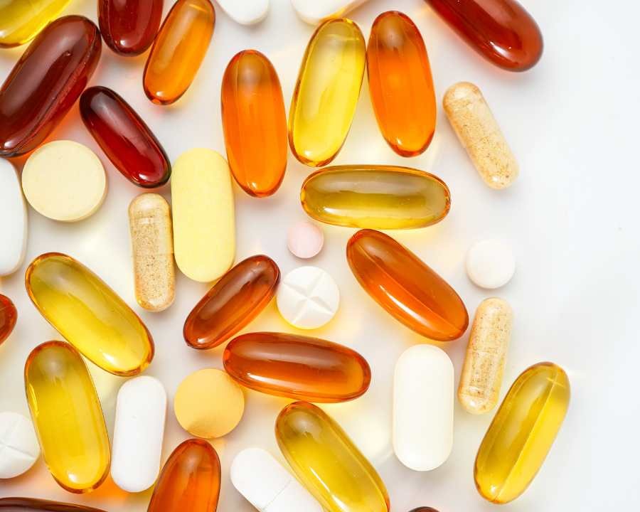 Mixed supplements including gel capsules and tablets scattered on white background – The Good Stuff nutrition and wellness range