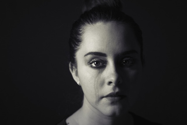 A black and white image of a sad woman crying because she's experiencing menopause and vocal changes.