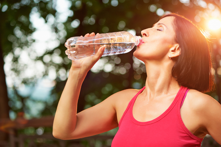 An image of a woman drinking water as part of her throat hygiene practices. 