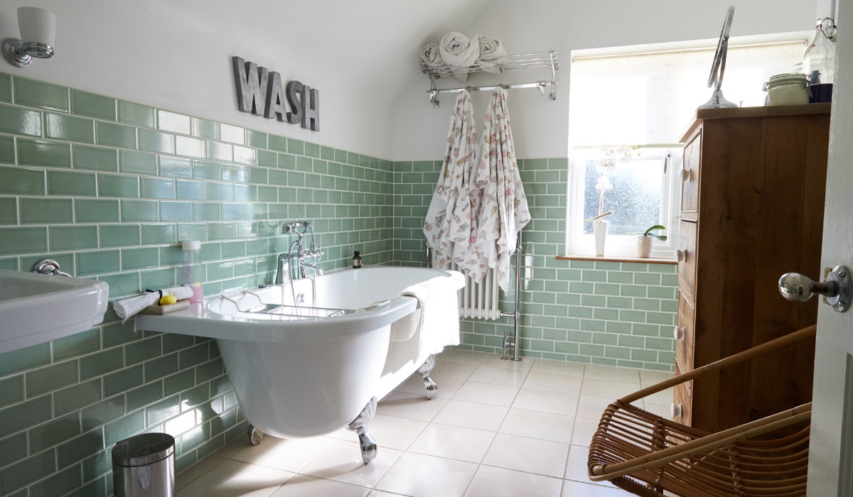Traditional bathroom with roll top bath and lime greem tiling