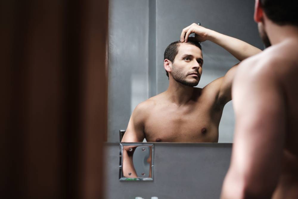 Man looking at his hair and hairline in the mirror