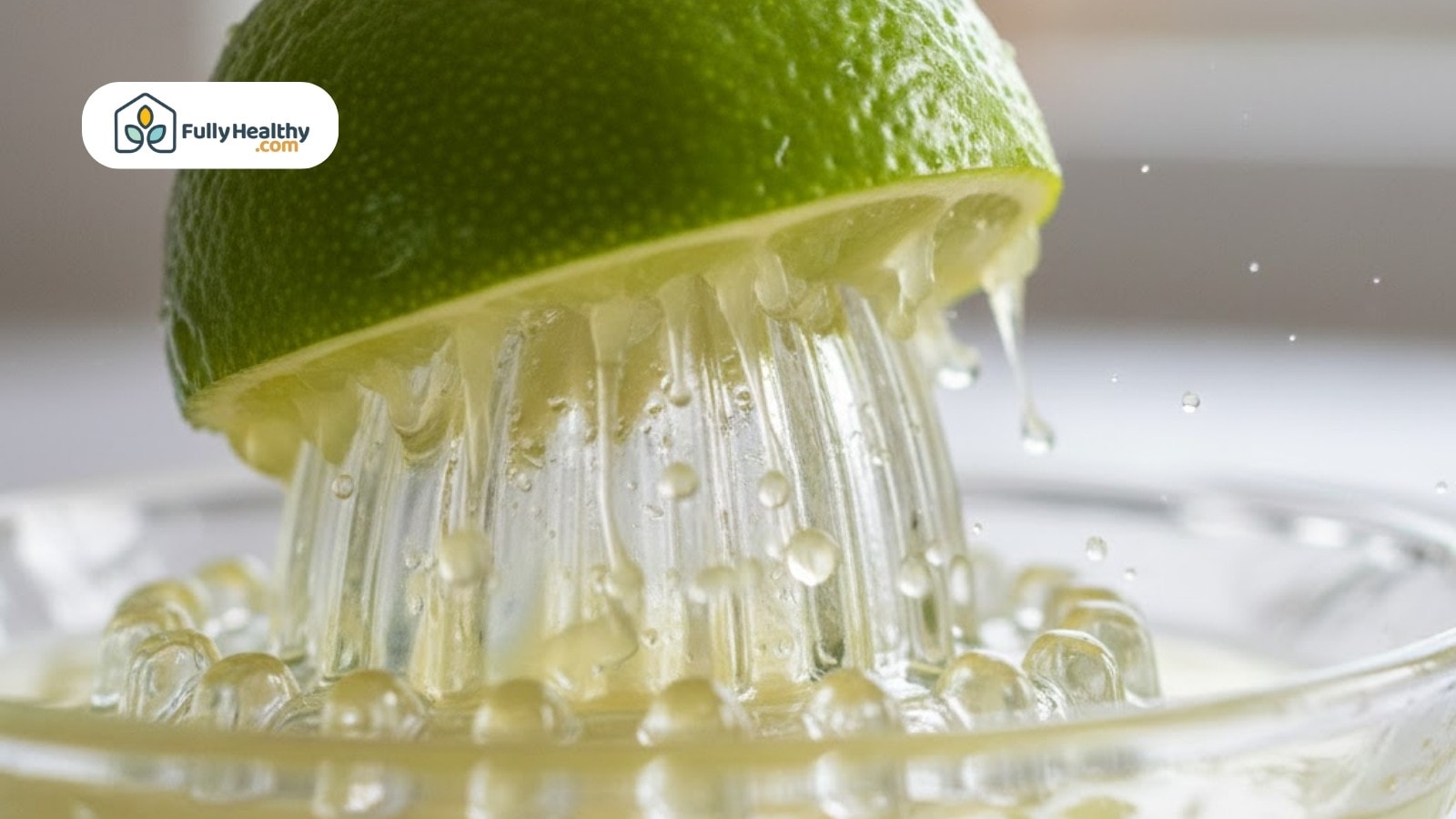Fresh lime being juiced with clear reamer splashing juice and droplets around