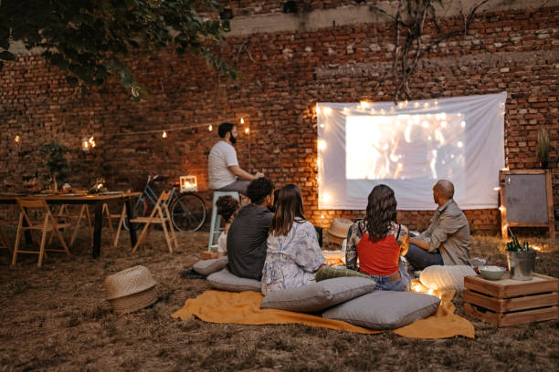 people sitting in front of a white sheet projector screen showing motion pictures
