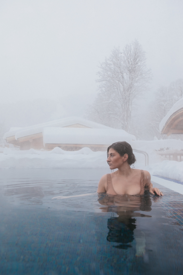 a woman sits in a hot tub outside during winter