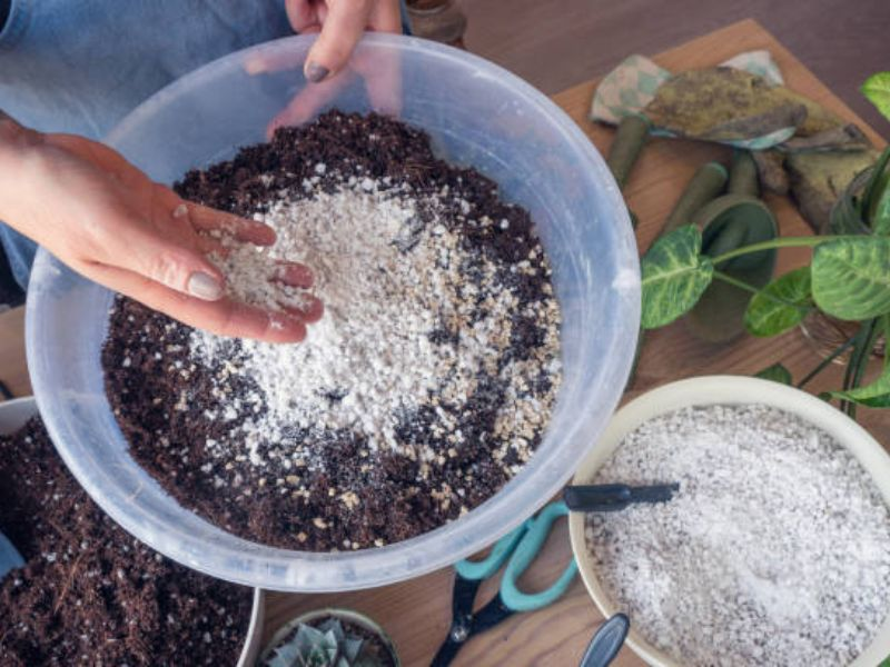 An individual gently mixing low nitrogen fertilizer into the soil.