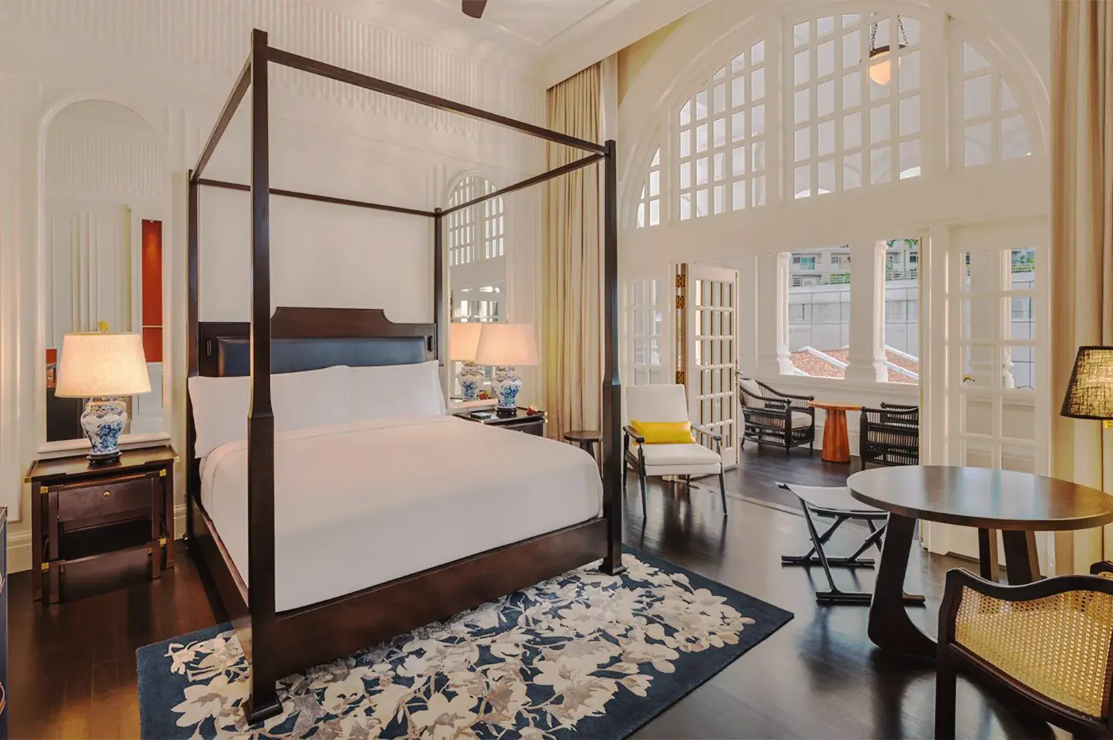 Elegant Raffles Hotel suite in Singapore with four‑poster bed, arched windows, and classic colonial interior design