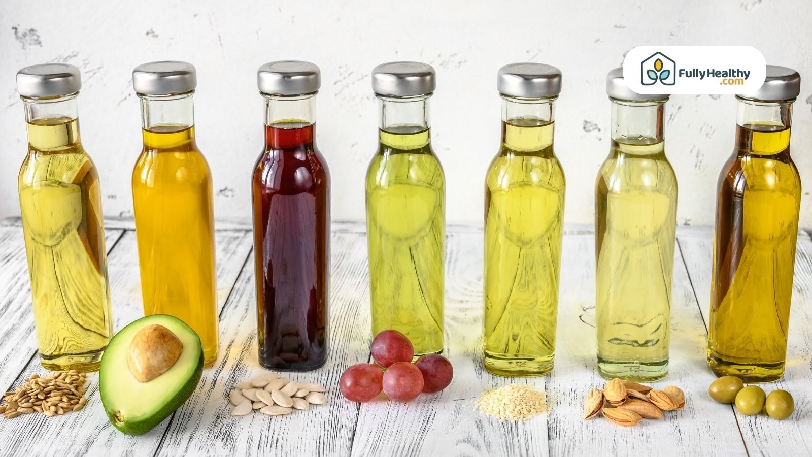 Variety of seed oils in bottles with avocado and grapes