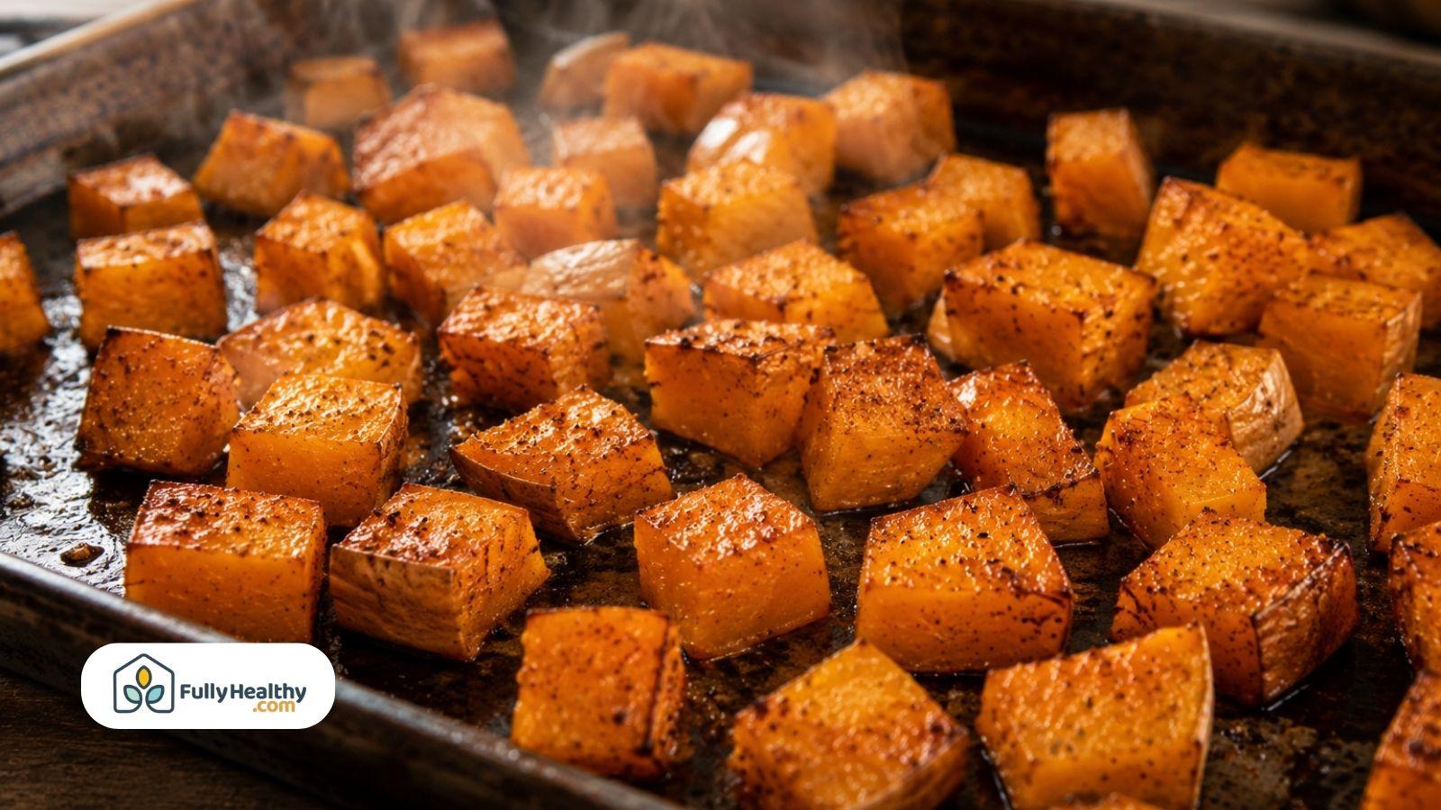 Roasted butternut squash cubes with crispy skin cooking on baking sheet