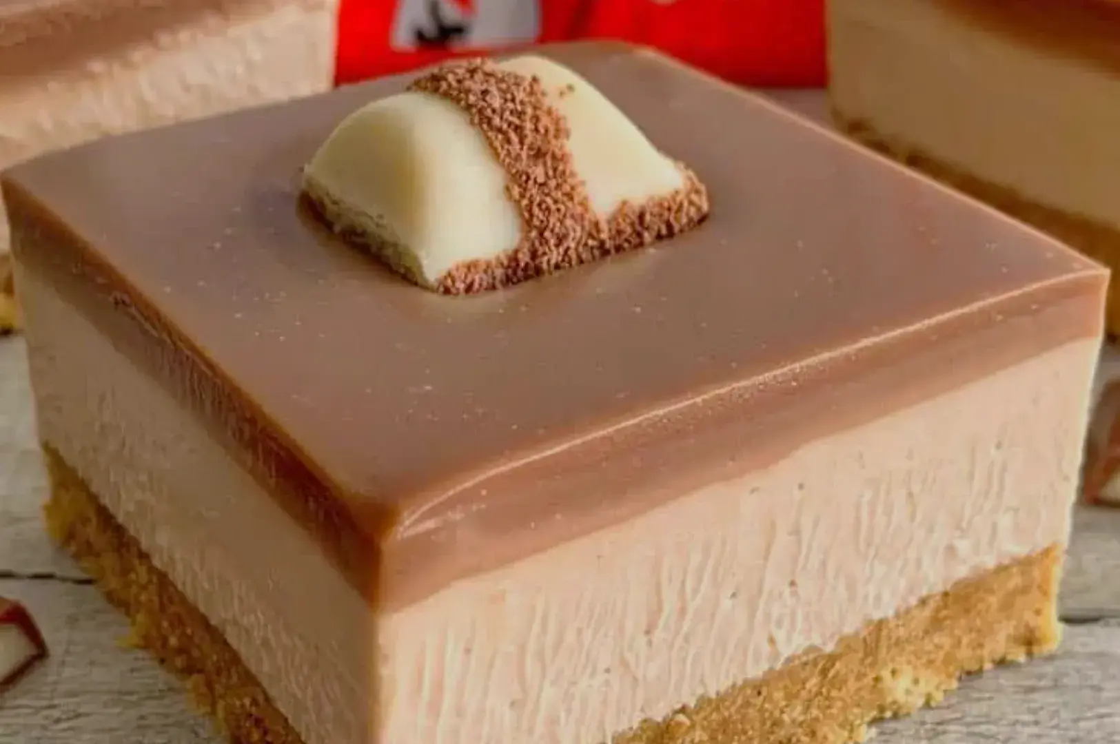 A close-up of a slice of chocolate dessert with a smooth, glossy top layer and a crumbly crust.