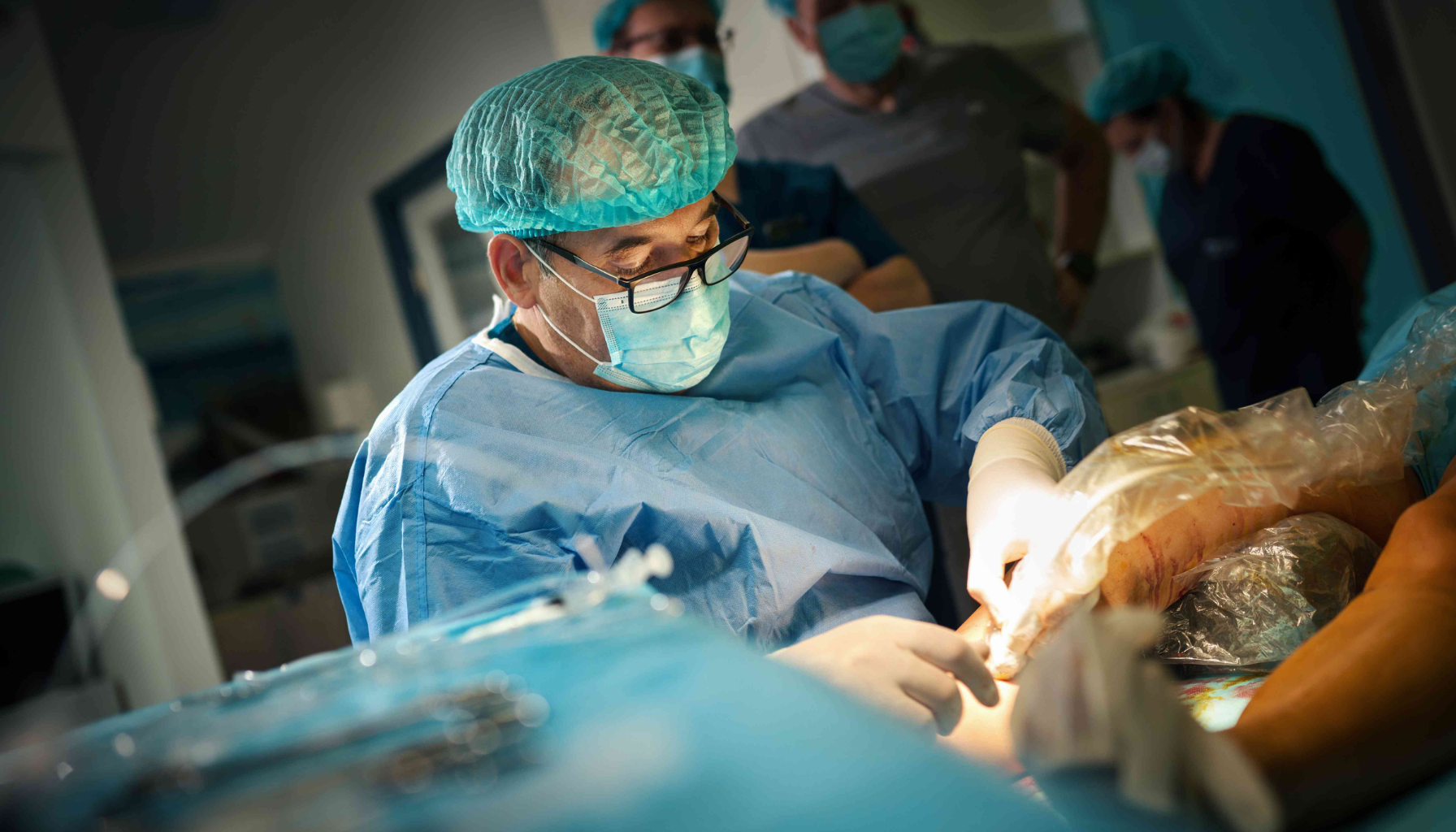 Kirurg i blå frakk og munnbind opererer pasientens tannkjøtt under sterilt inngrep.