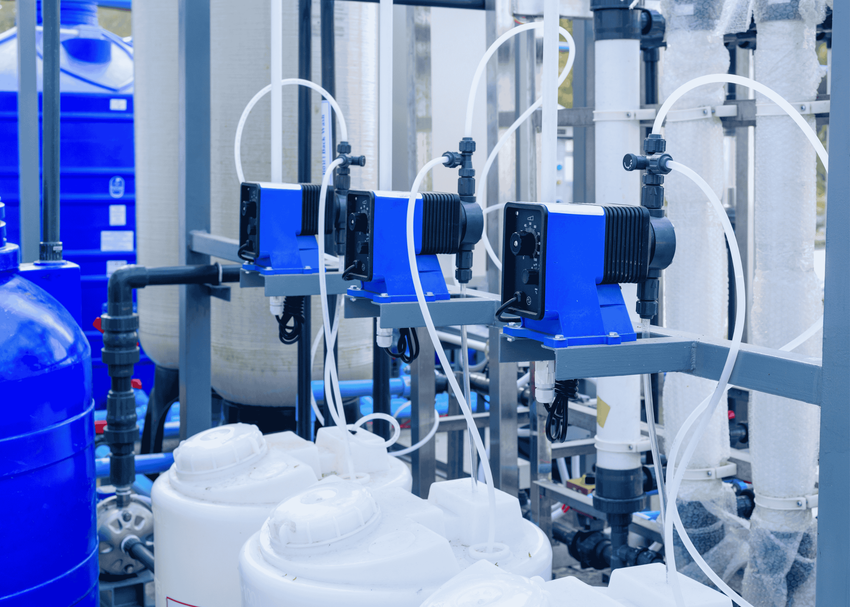 Close-up of chemical feed pumps with solution tanks in a water treatment system, showing dosing equipment used for reliable chemical feed applications.